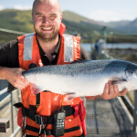 A Mowi farm manager holding a salmon