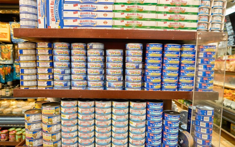 A set of shelves with tuna cans
