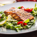 A grilled salmon fillet on a bed of greens