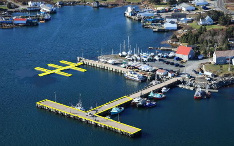 An aerial view of a small craft harbor in Canada with a wharf and floating dock highlighted in a yellow outline