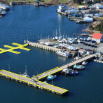 An aerial view of a small craft harbor in Canada with a wharf and floating dock highlighted in a yellow outline