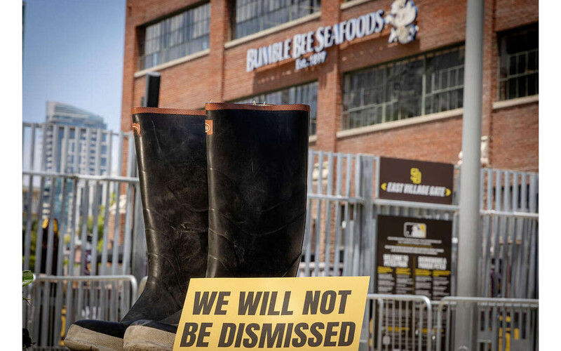 A pair of boots with a sign saying "we will not be dismissed" in front of Bumble Bee Seafoods headquarters