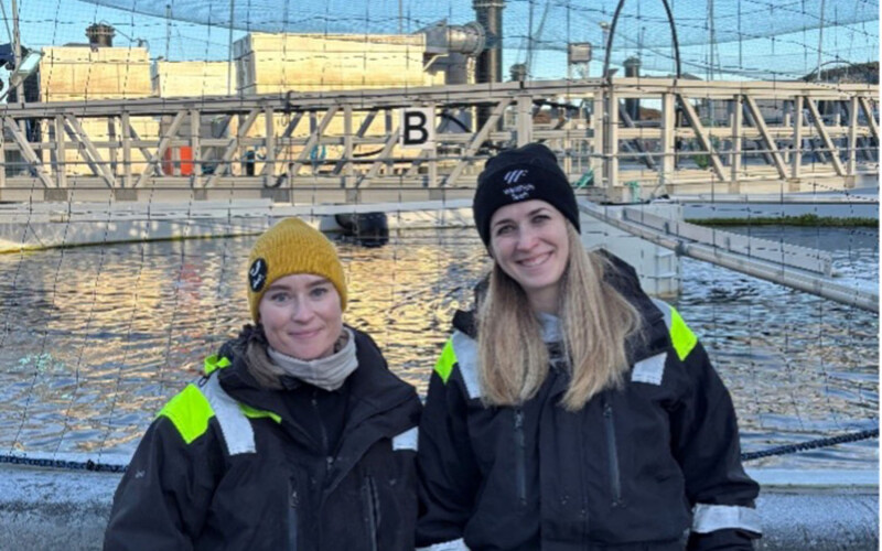 Two people standing at a salmon farm