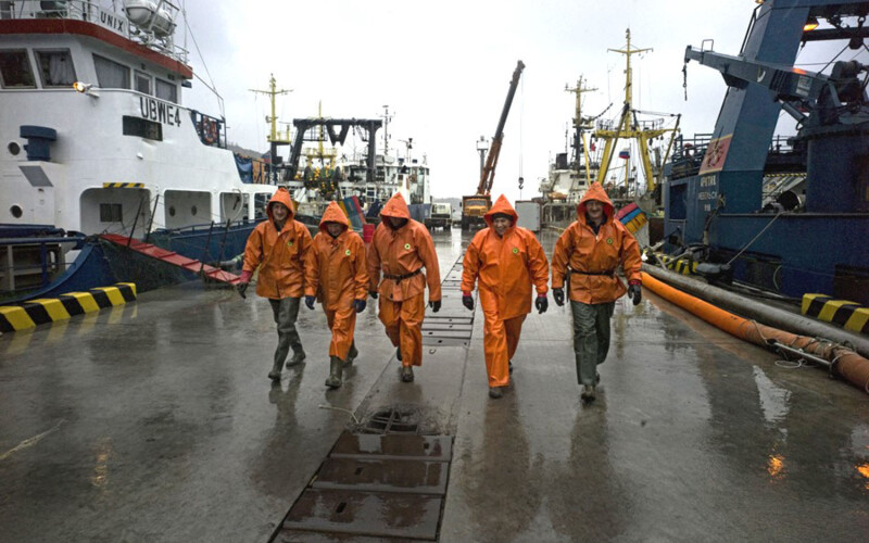 Five fishermen walking at a fishing wharf