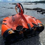 A Meox robot sitting on a dock next to the water