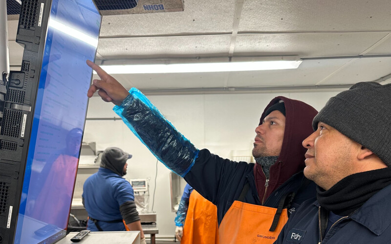 Two men pointing at a screen including a BlueTrace interface