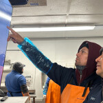 Two men pointing at a screen including a BlueTrace interface