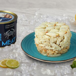 A pile of crab on a plate next to a can featuring the product label