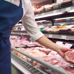 A retail shopper picking up beef