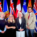 Canadian officials standing in front of the country's national and provincial flags