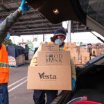 A person at a food bank placing food in the trunk of a car