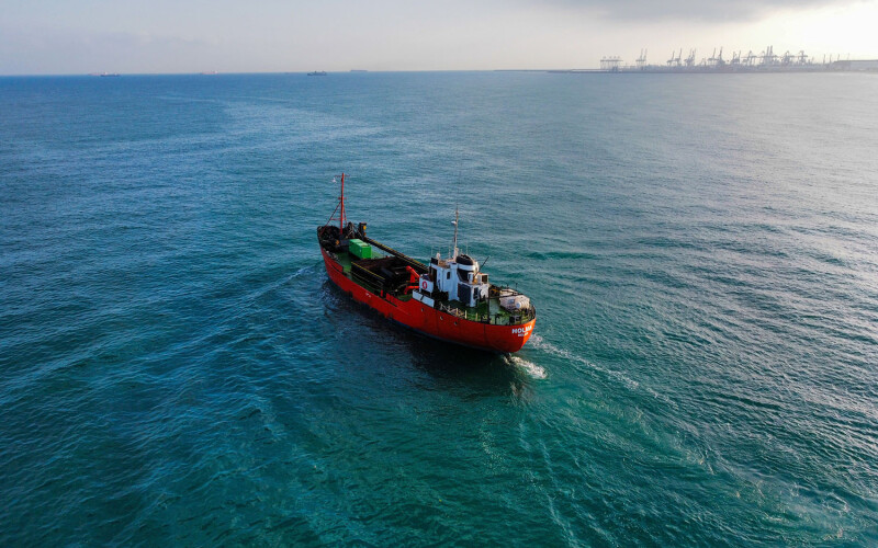 A red vessel sailing across the ocean