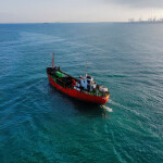 A red vessel sailing across the ocean