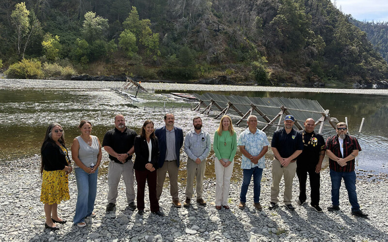 Tribal and government officials standing on a river bank