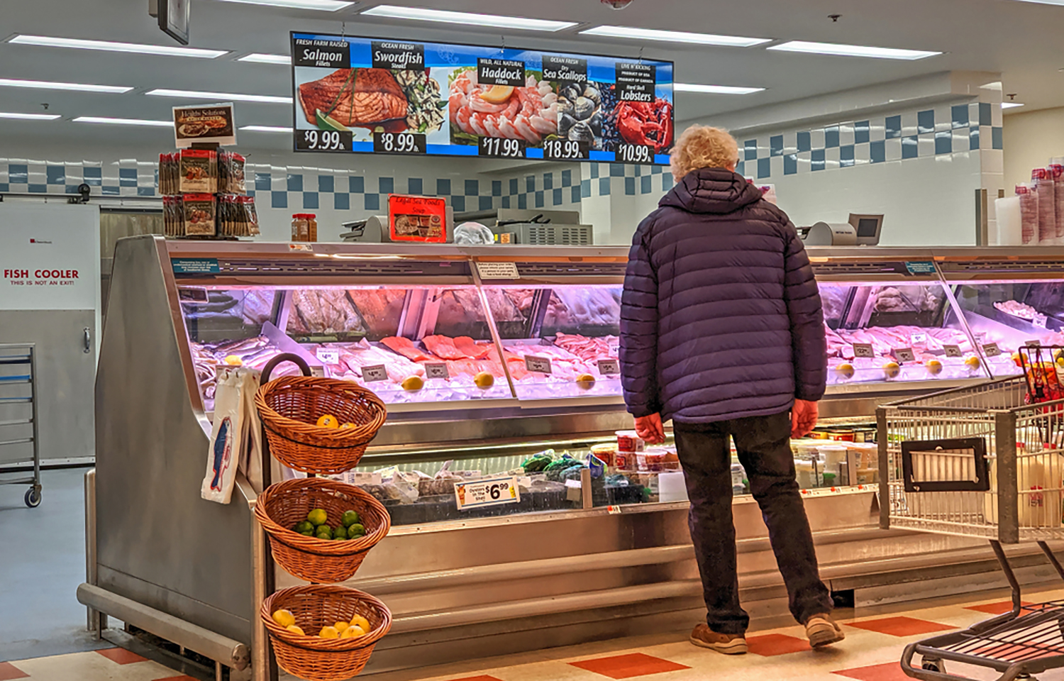 A woman standing at a seafood counter in a grocery store