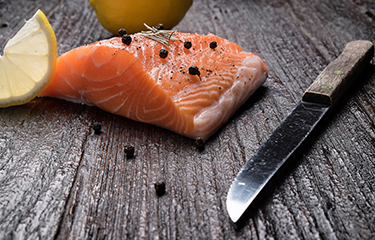 A salmon fillet with capers and a knife