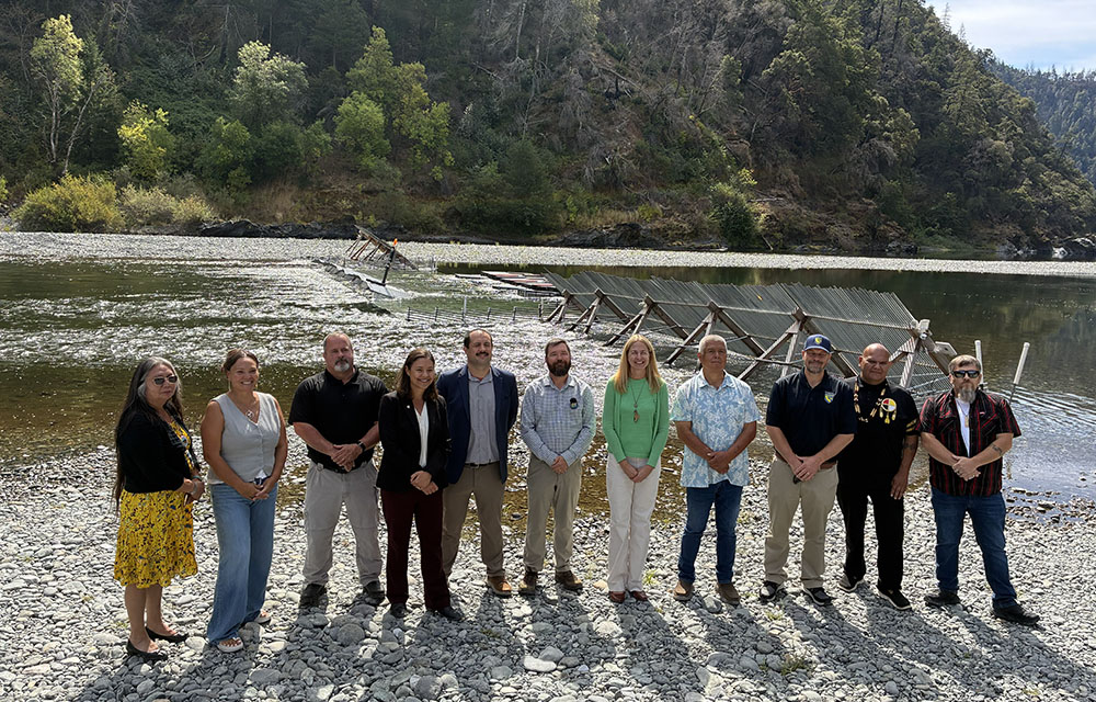 Tribal and government officials standing on a river bank