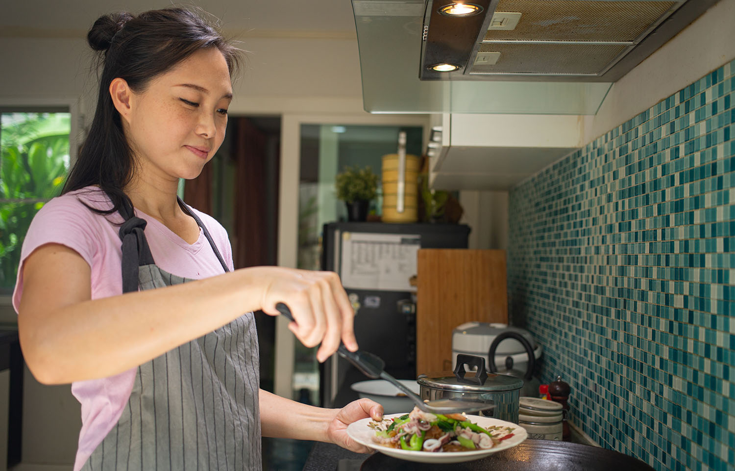 A woman cooking a seafood noodle dish at home