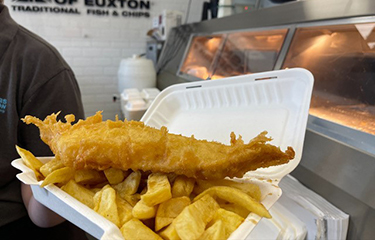 Someone holding up fish and chips from a shop in the U.K.