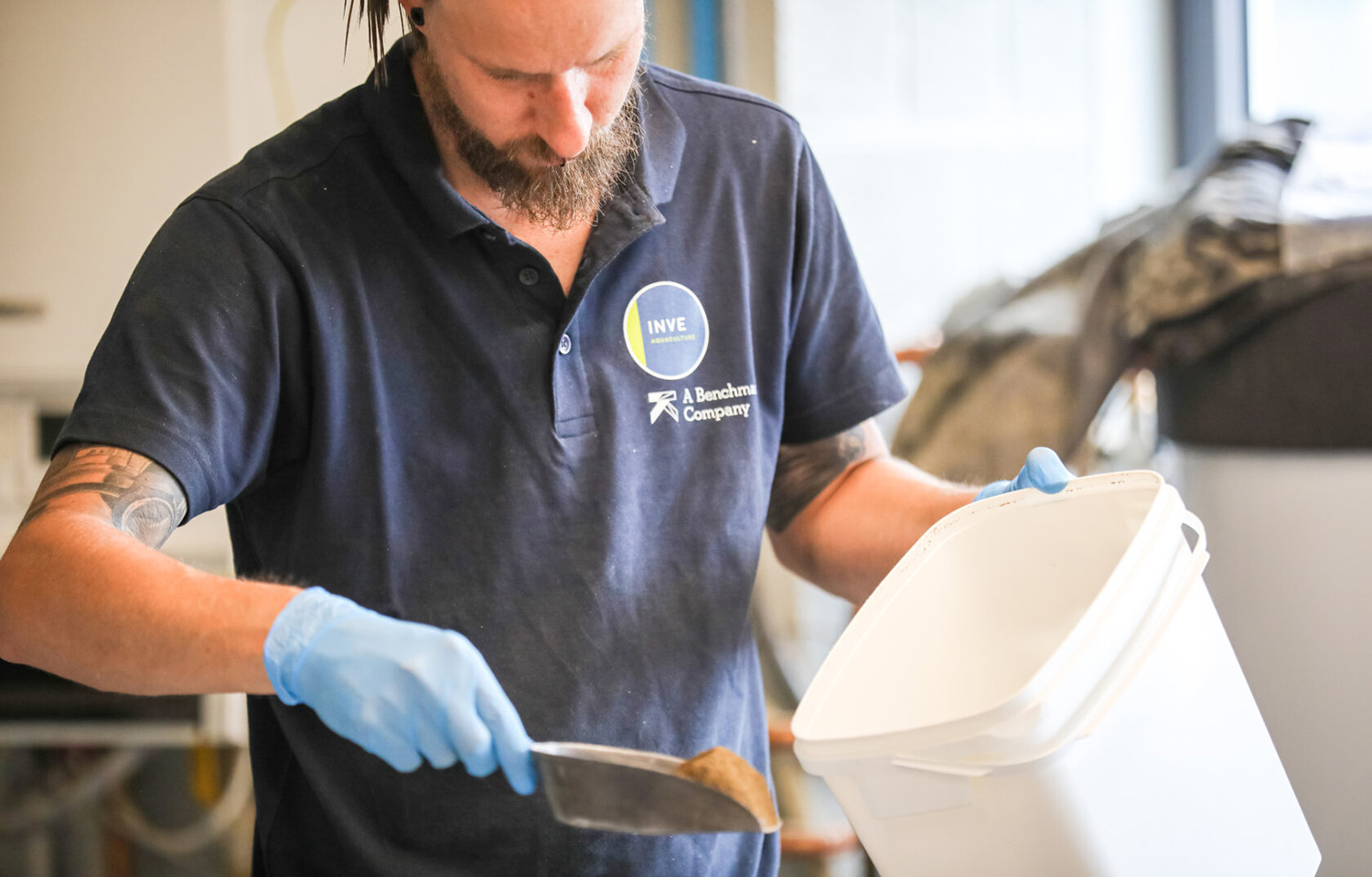A Benchmark Holdings employee scooping aquaculture feed