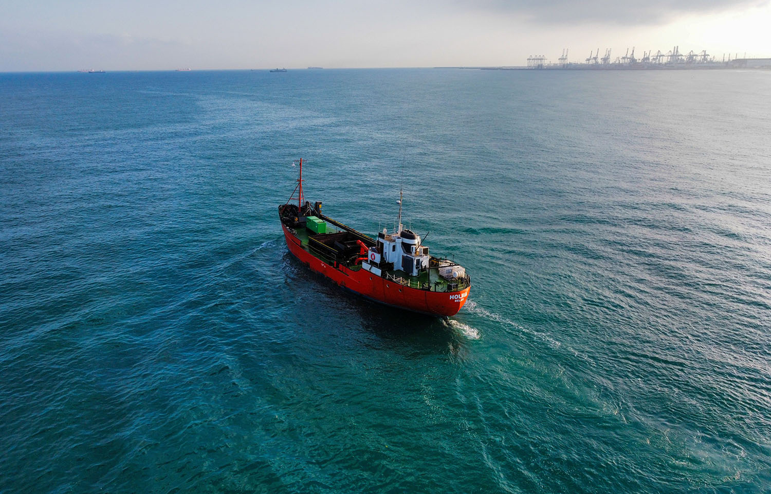 A red vessel sailing across the ocean