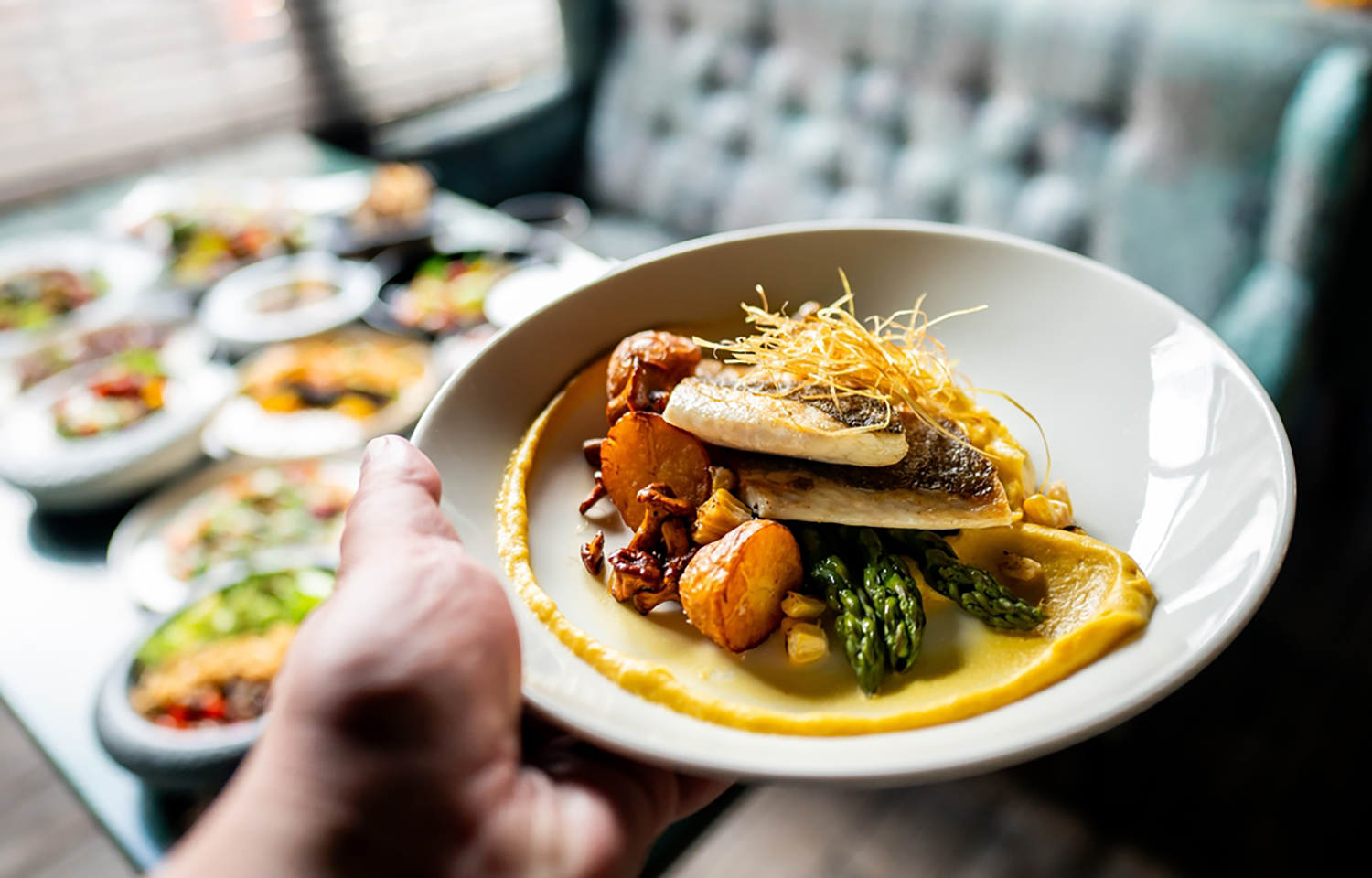 A person holding out a seafood dish at a restaurant