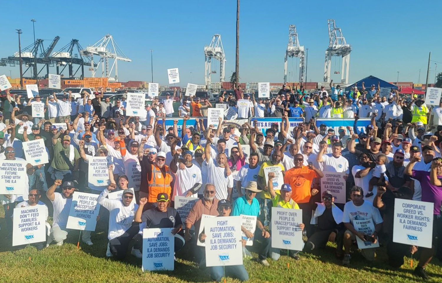 A large group of International Longshoreman's Association members posing with picket signs at a port.