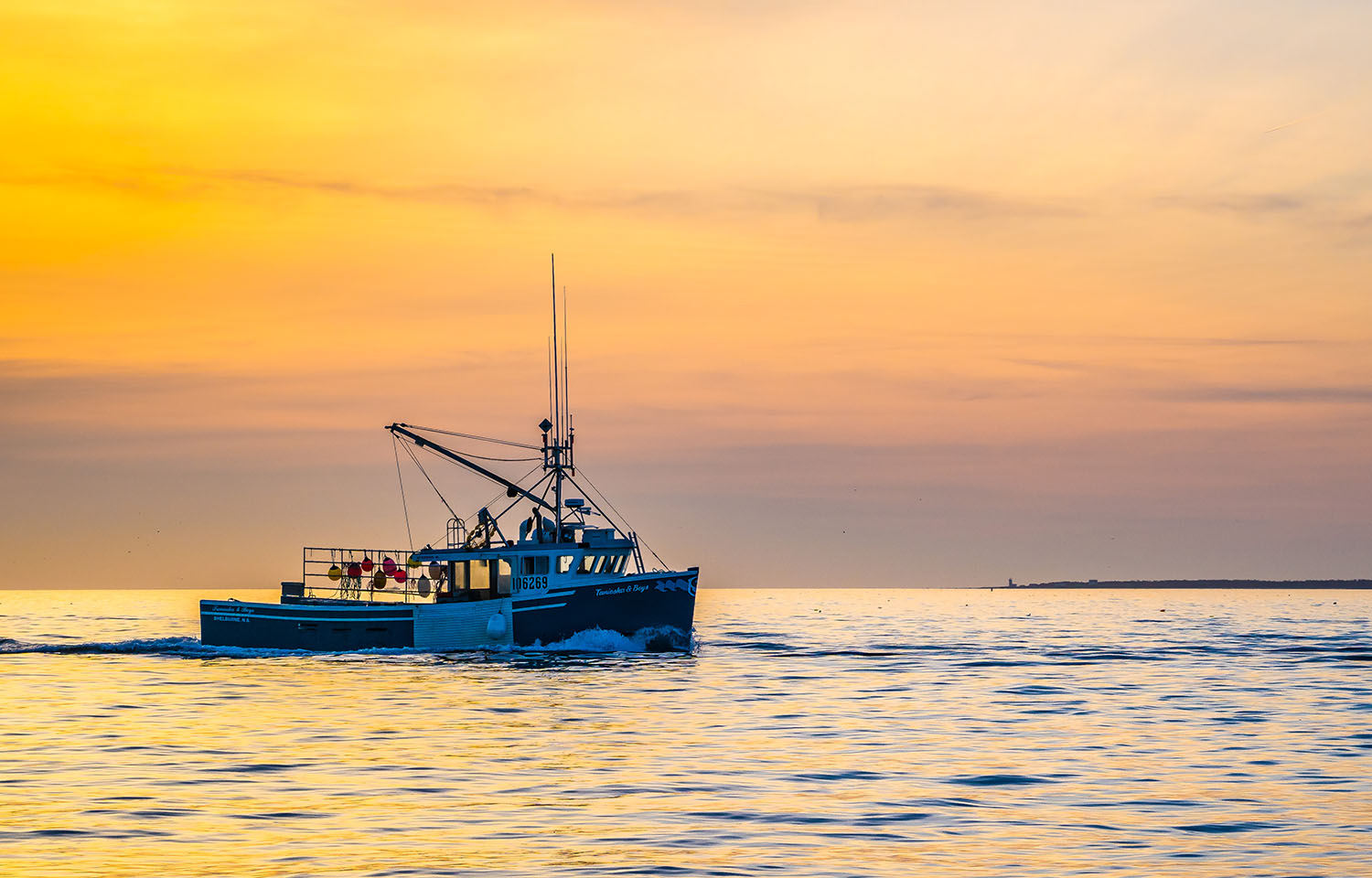 A lobster boat in Nova Scotia sailing at sunrise.