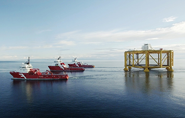 Three boats tow the large ocean-based salmon farming pen known as Ocean Farm 1